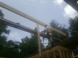 Carpenter setting a ridge beam over a new addition frame — Ice Dam Removal by Roofing Brothers in Leasburg