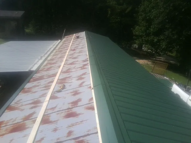 Old rusted panels beside newly installed green metal roofing — Wind Damage Roof Repair by Roofing Brothers in Leasburg