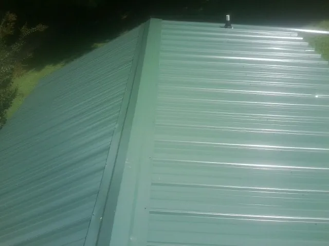 New green metal panels meeting at the ridge of a roof — Flat Roof Repair work by our crew in Leasburg