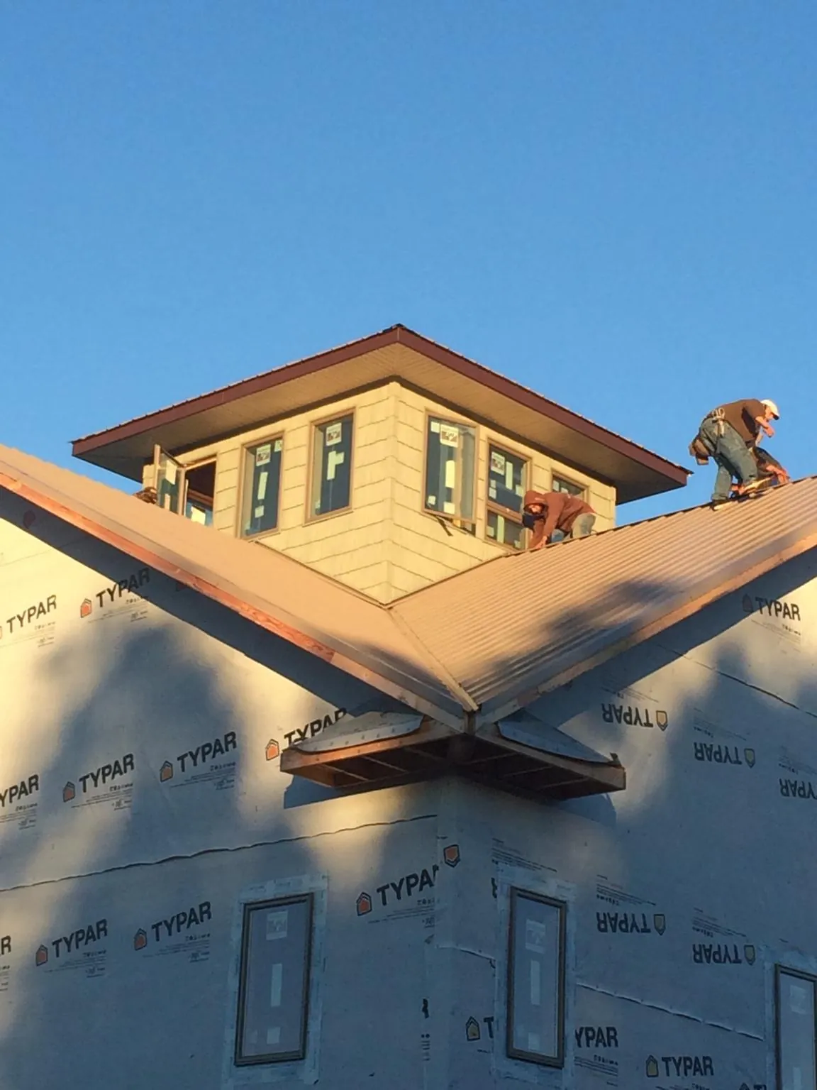 Roofers working around a rooftop cupola on a new metal roof at sunset — Roof Waterproofing in Leasburg by Roofing Brothers